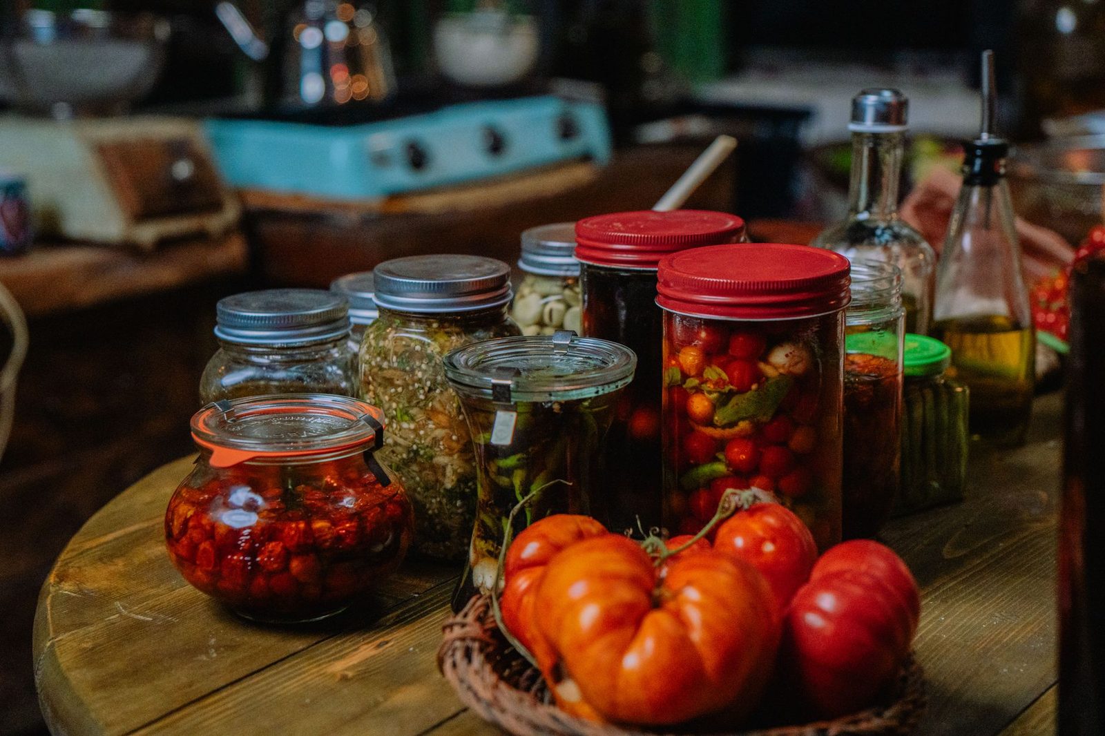 A cozy indoor kitchen setup featuring various preserved vegetables in jars, alongside fresh produce.