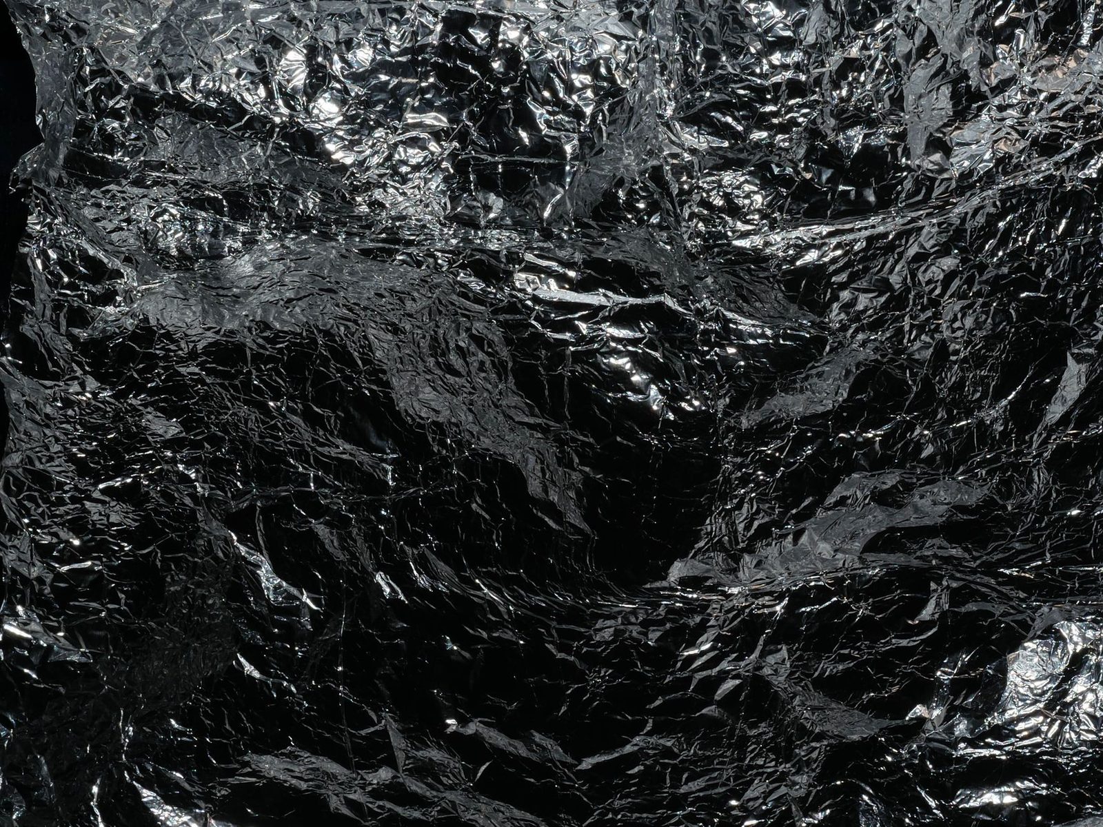 Reflective crumpled silver foil texture, ideal for backgrounds or abstract designs.