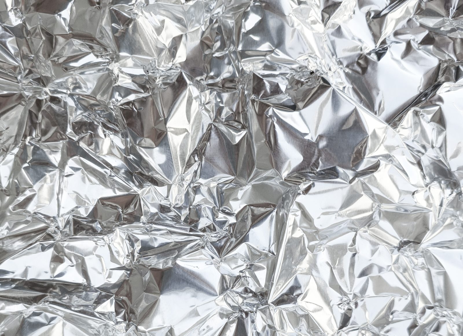 Close-up of a crumpled silver aluminum foil texture, perfect for creative backgrounds.