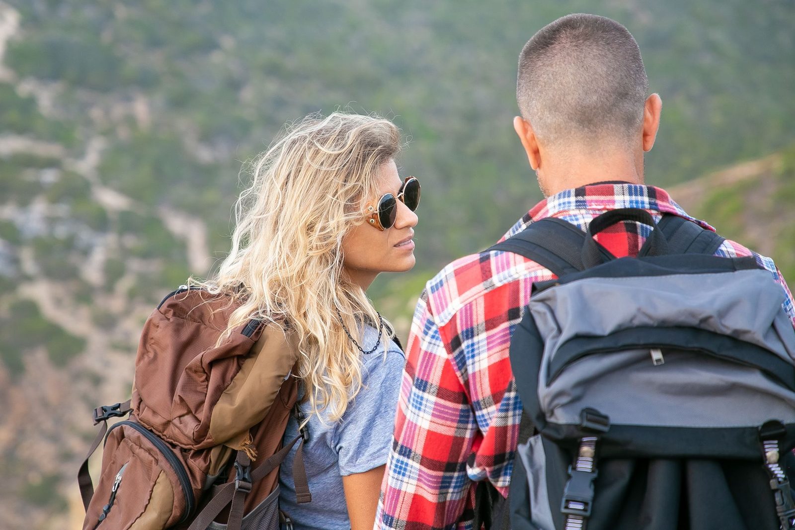 A young couple hiking in Portugal, enjoying the scenic outdoors with backpacks.