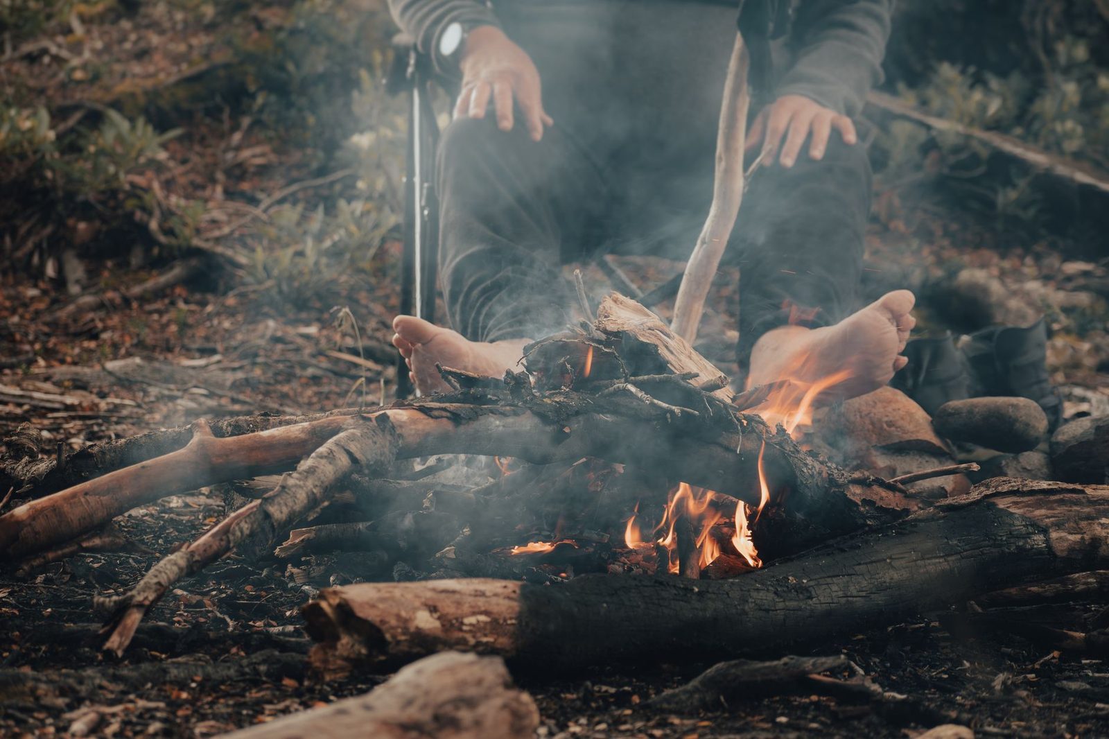 A man seated by a campfire outdoors, enjoying a peaceful time with nature.