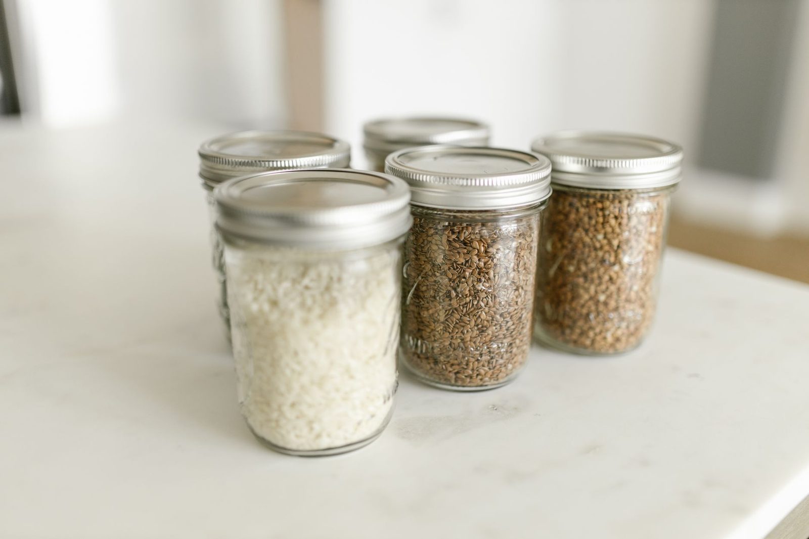 Close-up of glass jars filled with rice and grains on a kitchen counter, ideal for storage.