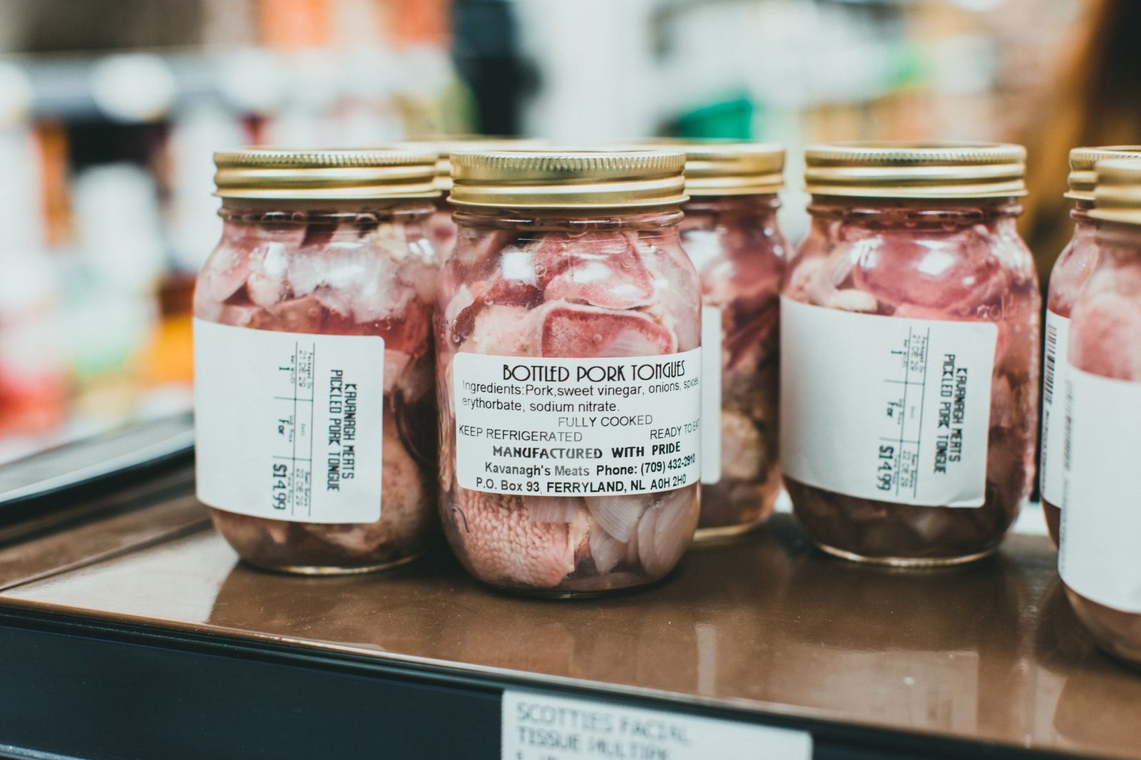 Detailed close-up shot of bottled pork tongues on display in a supermarket.
