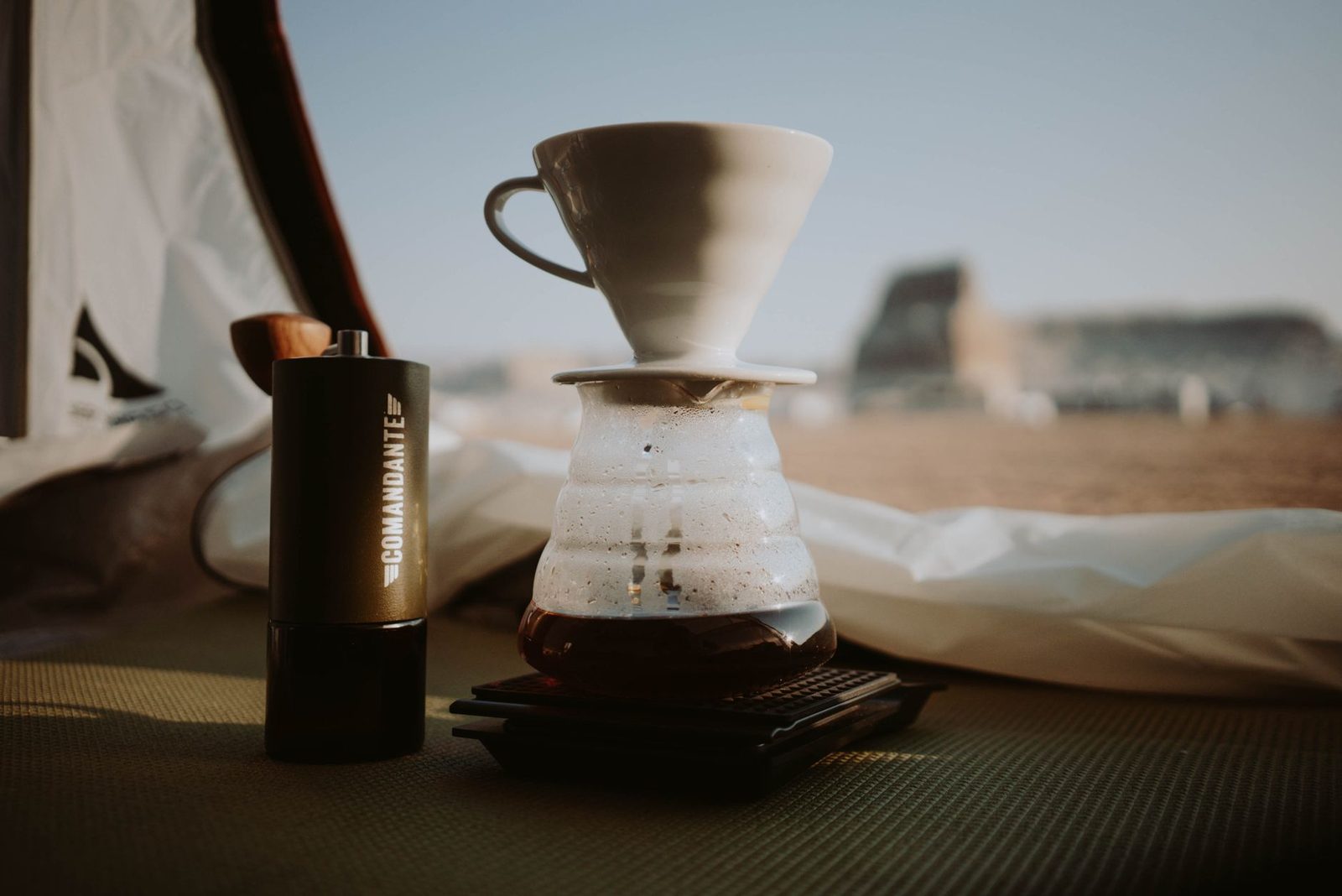 Pour over coffee maker with coffee grinder in tent against majestic arid terrain on summer day