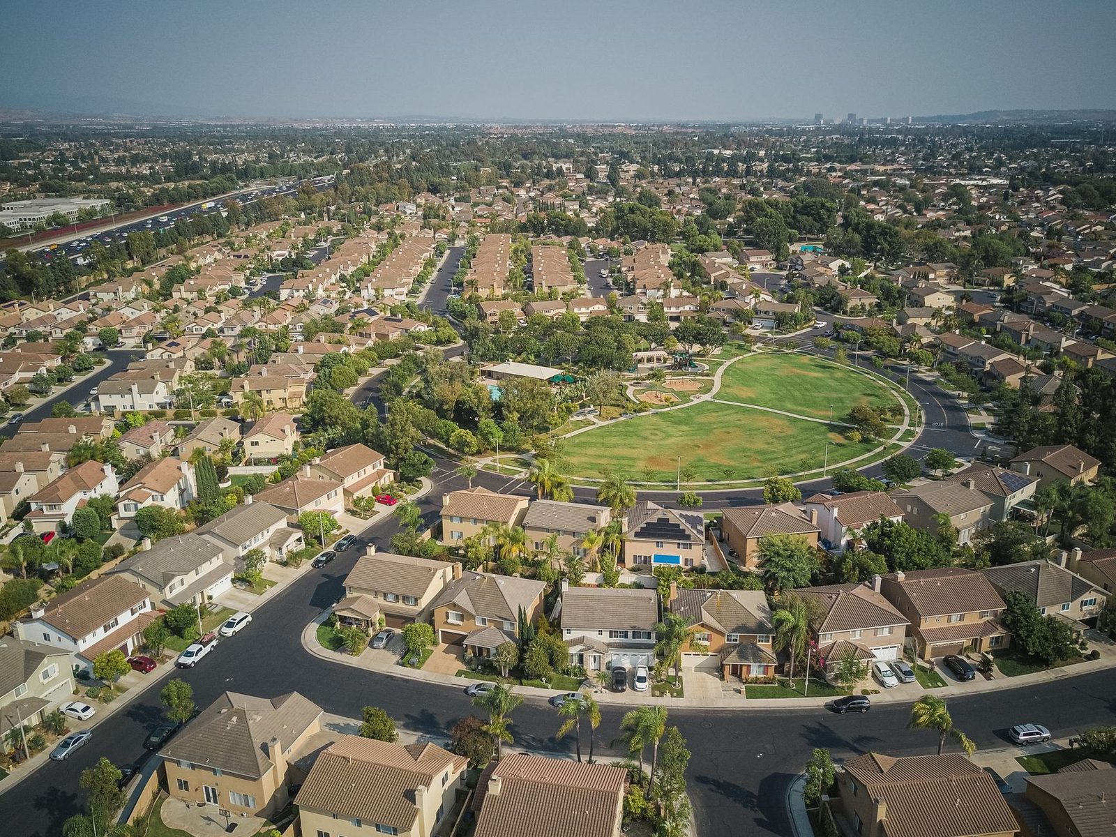 Drone shot of a spacious suburban neighborhood featuring a central park with numerous houses.