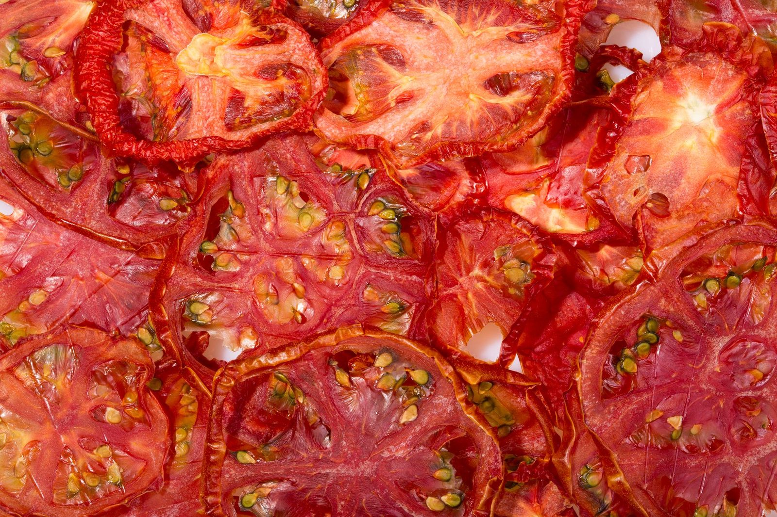 Close-up view of vibrant red dried tomato slices, ideal for backgrounds or culinary content.