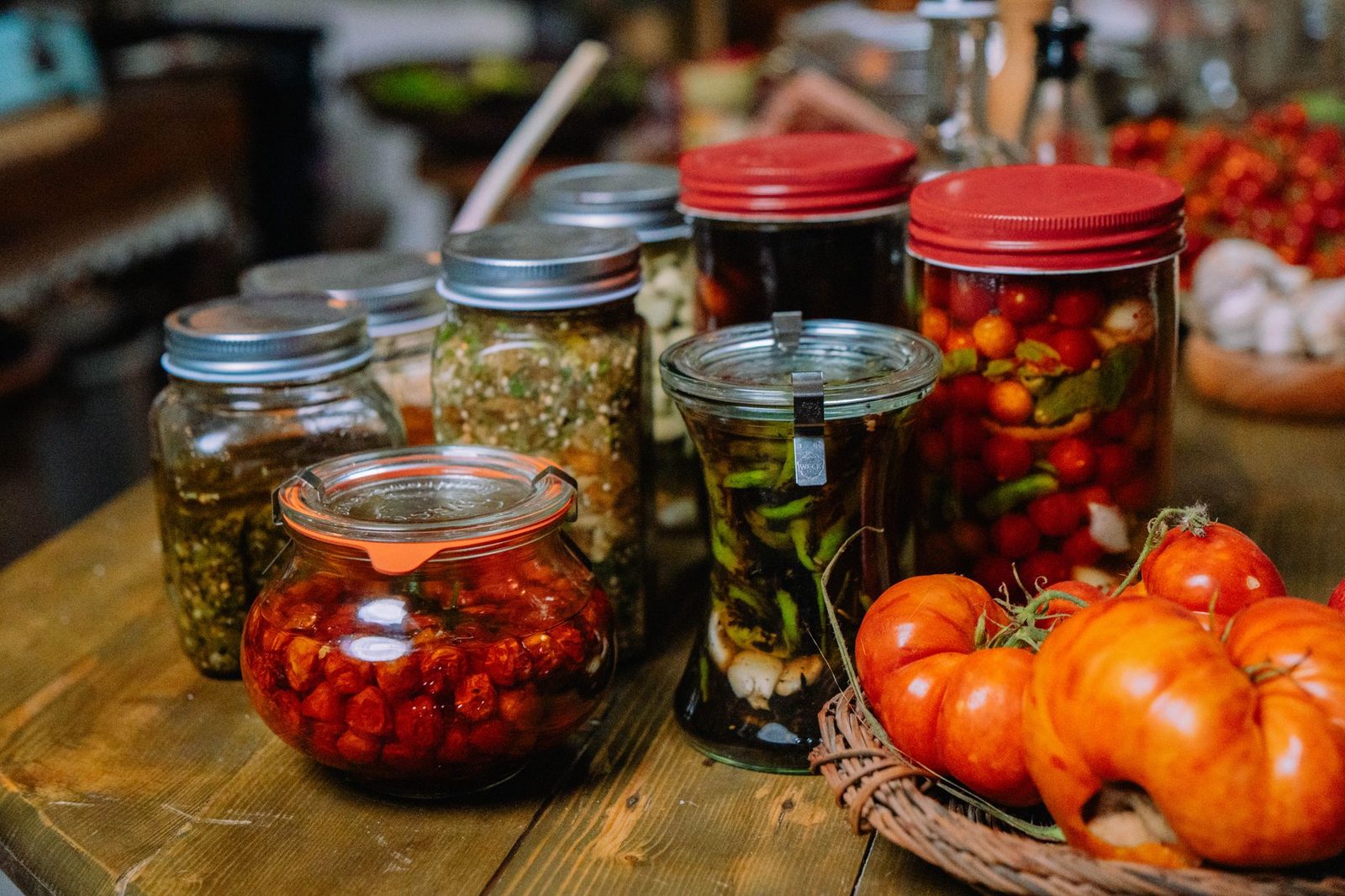Colorful jars of homemade preserved vegetables and pickles on a rustic wooden table.