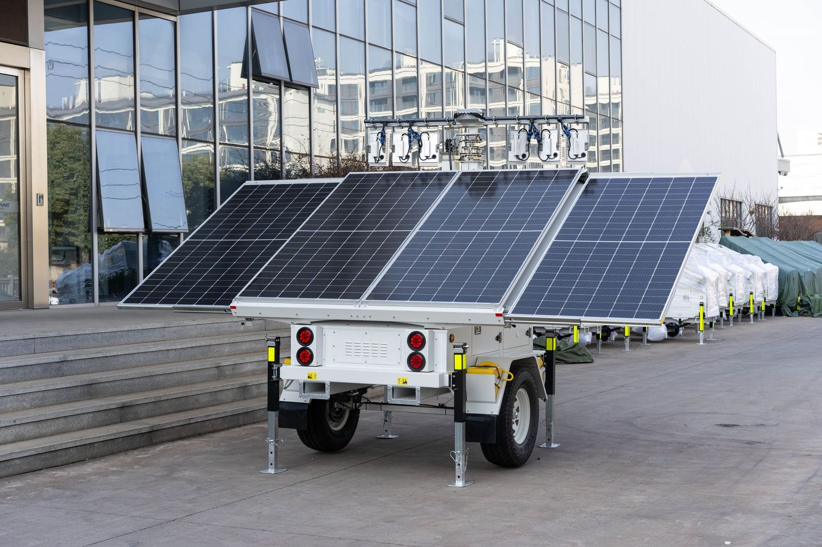 A mobile solar panel trailer parked outdoors by a modern building, showcasing renewable energy technology.