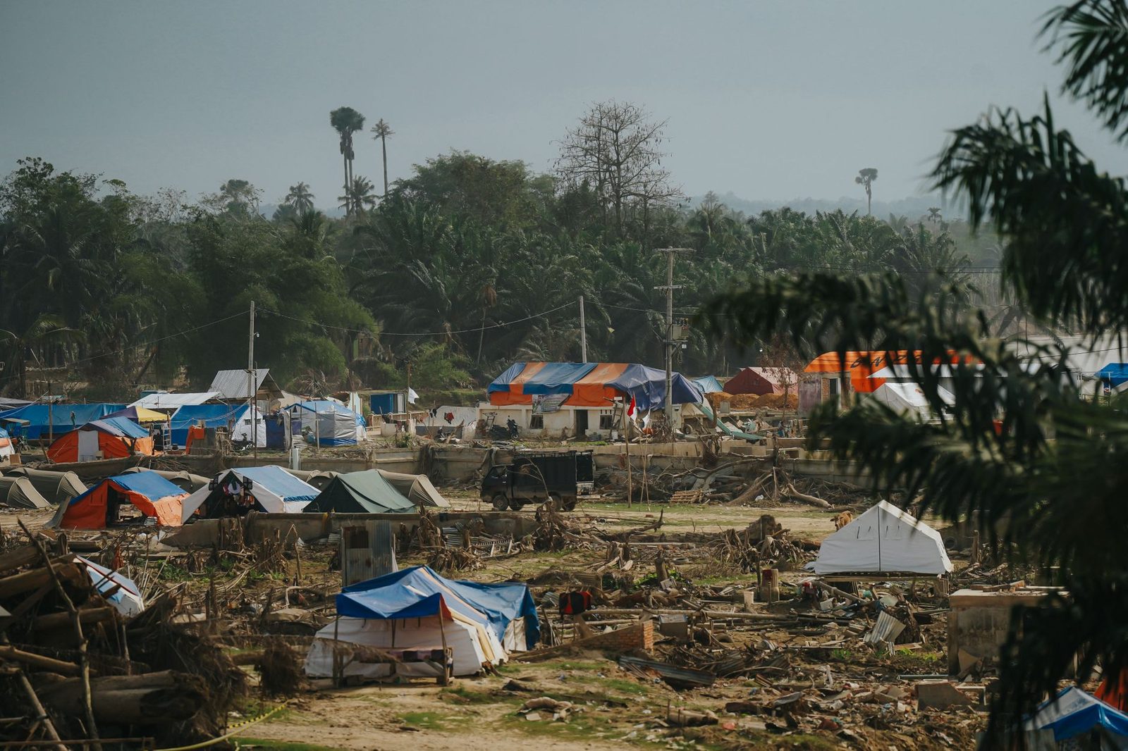 Temporary shelters in a disaster relief camp nestled in lush greenery in Aceh, Indonesia.