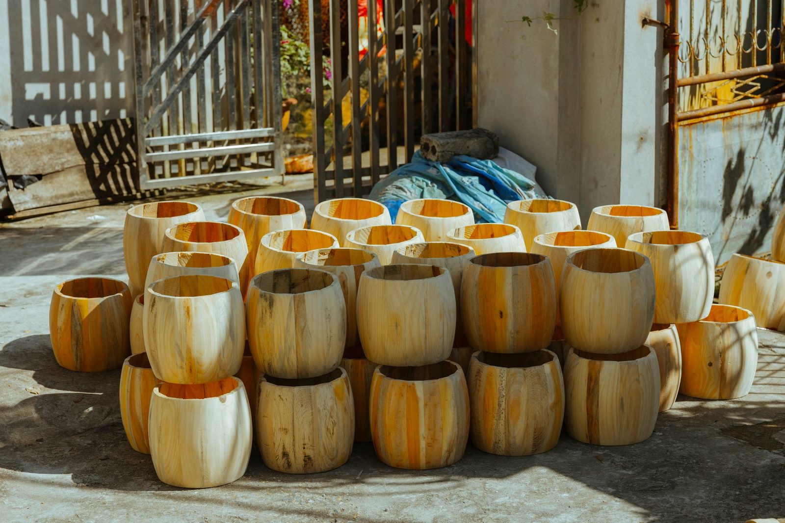 A collection of rustic wooden barrels stacked outside in natural sunlight.
