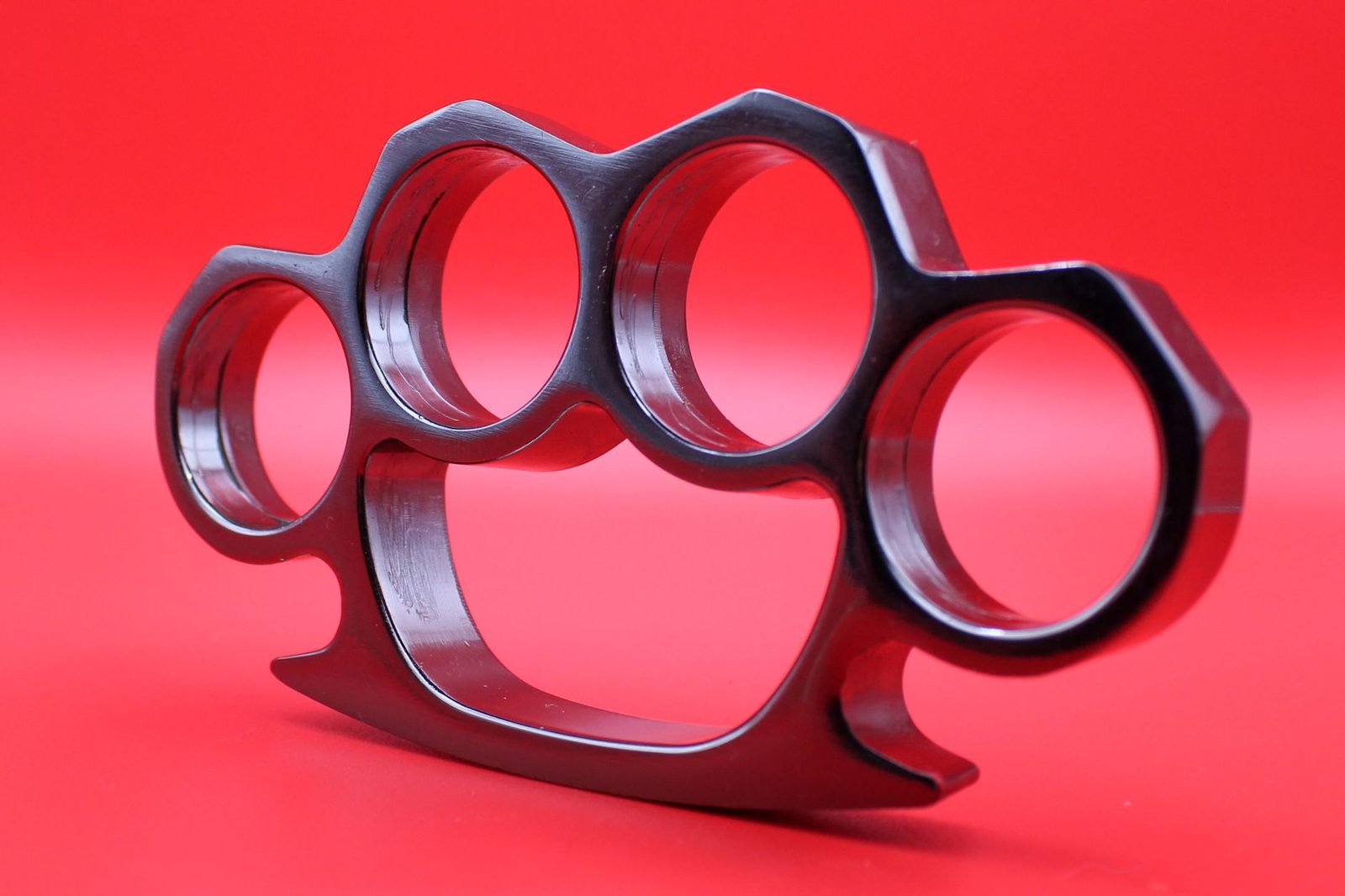 Detailed view of a metal brass knuckles on a vibrant red background.