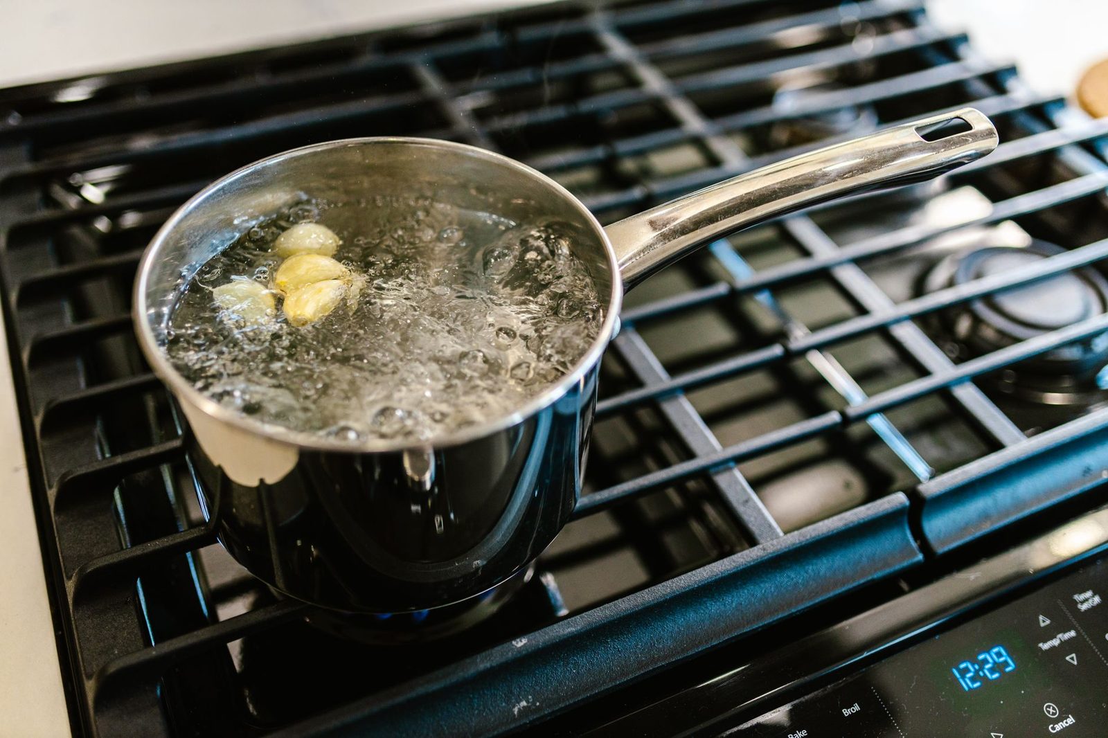 Close-up of garlic boiling in a pot on a stove, showcasing culinary preparation.