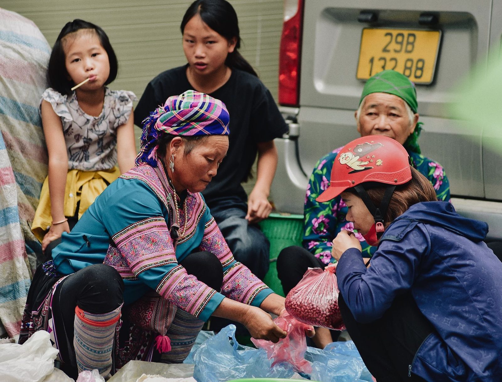 Hmong women and children engage in lively market trading outdoors.