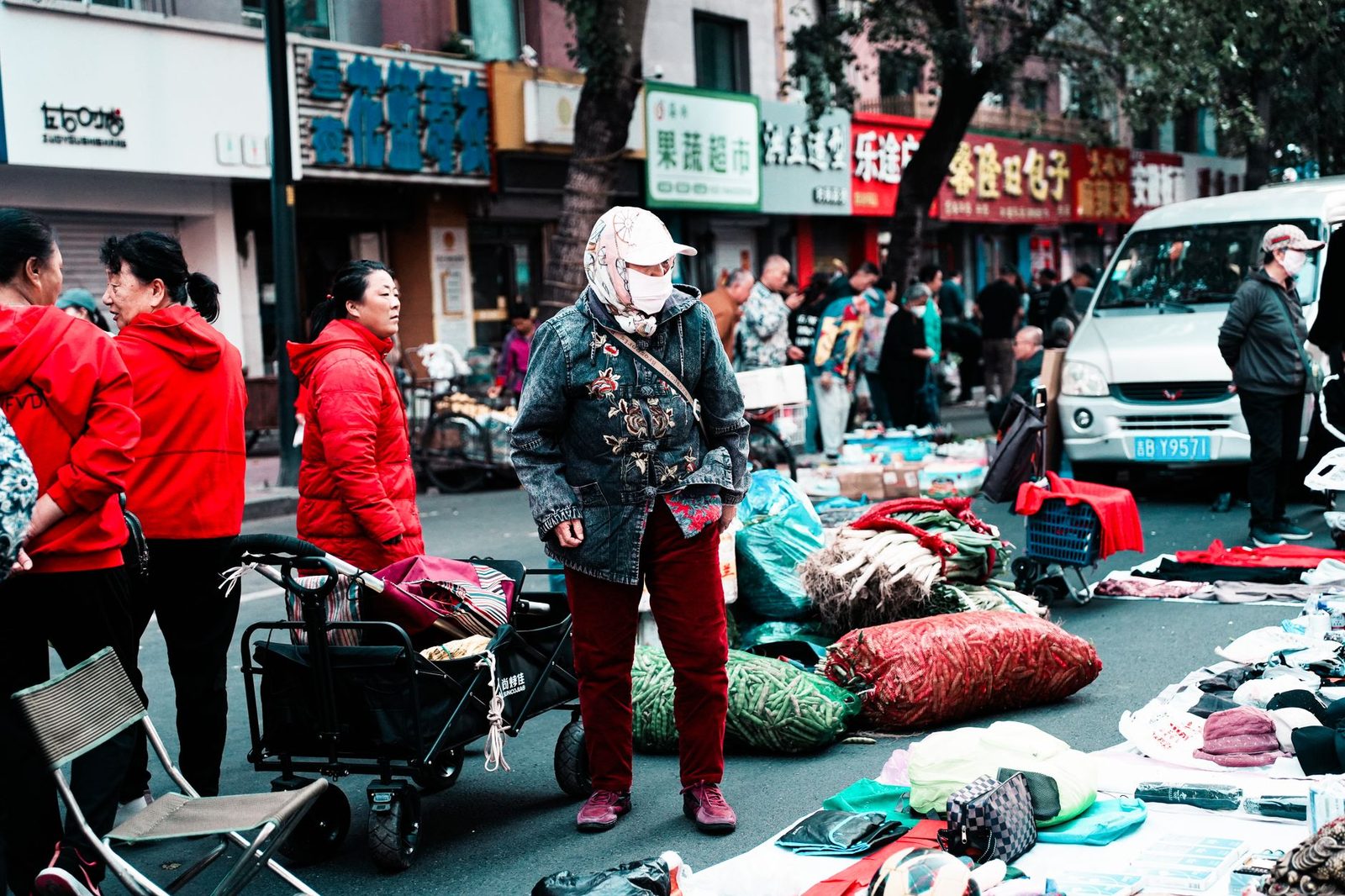 Vibrant street market in Chinatown with people shopping and interacting outdoors during the day.