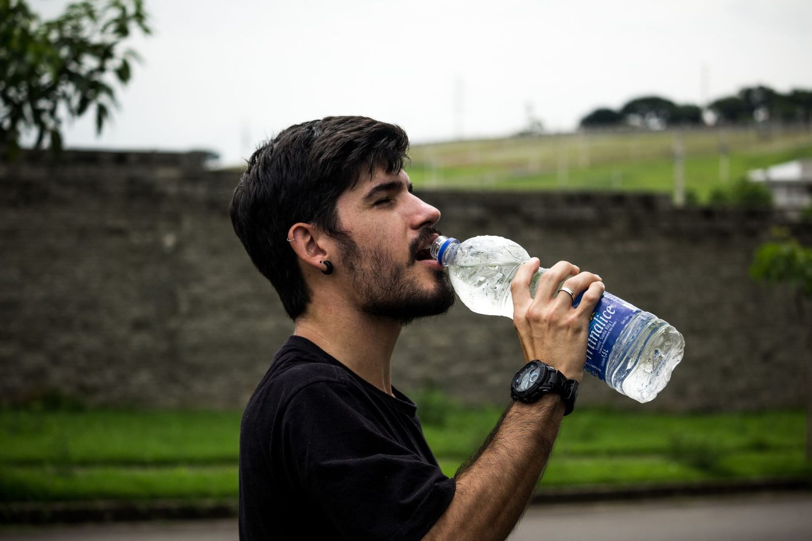 A young man drinks bottled water outside, staying hydrated and refreshed.