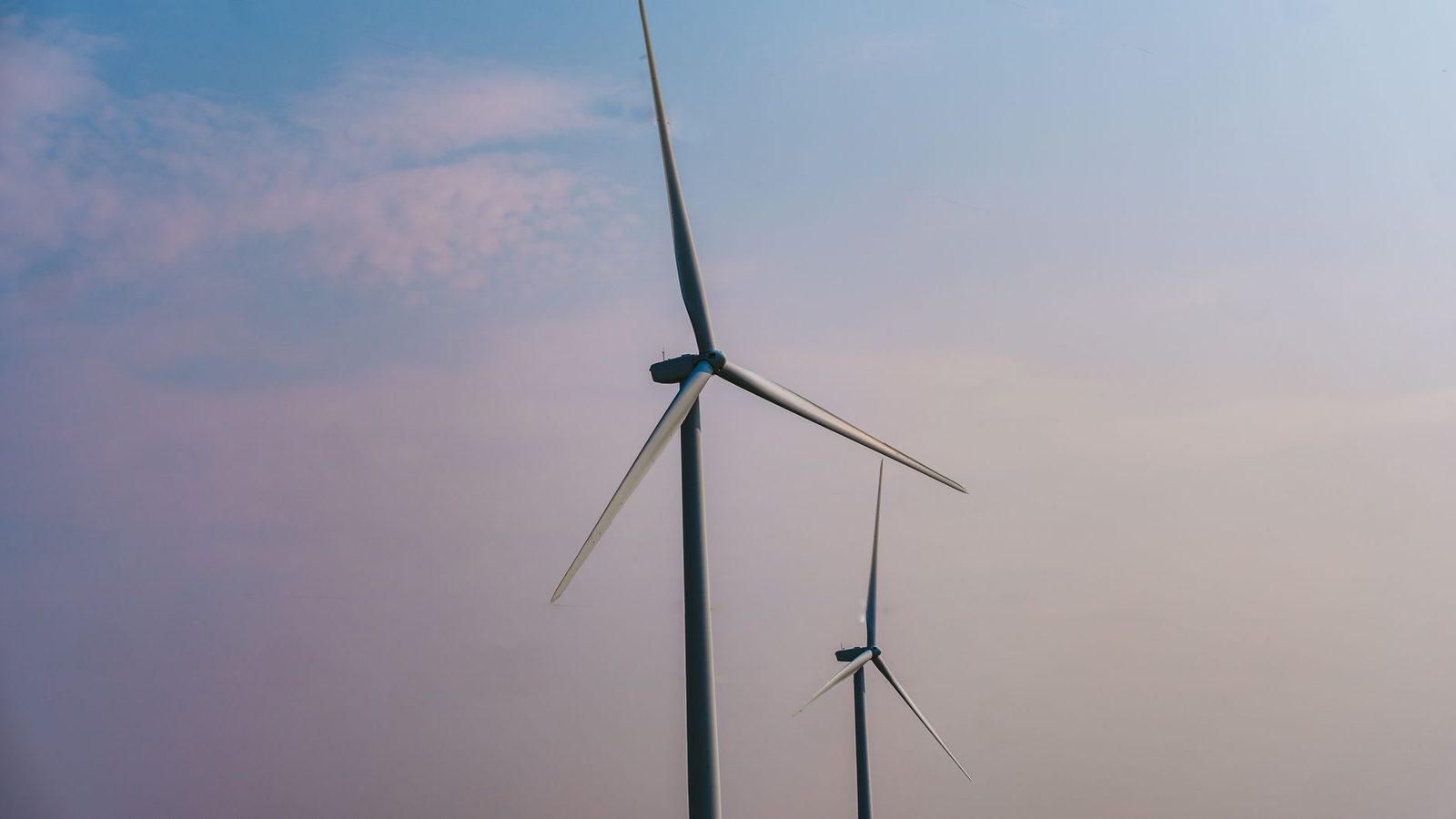 Two wind turbines stand tall under a clear sky, emphasizing renewable energy solutions.