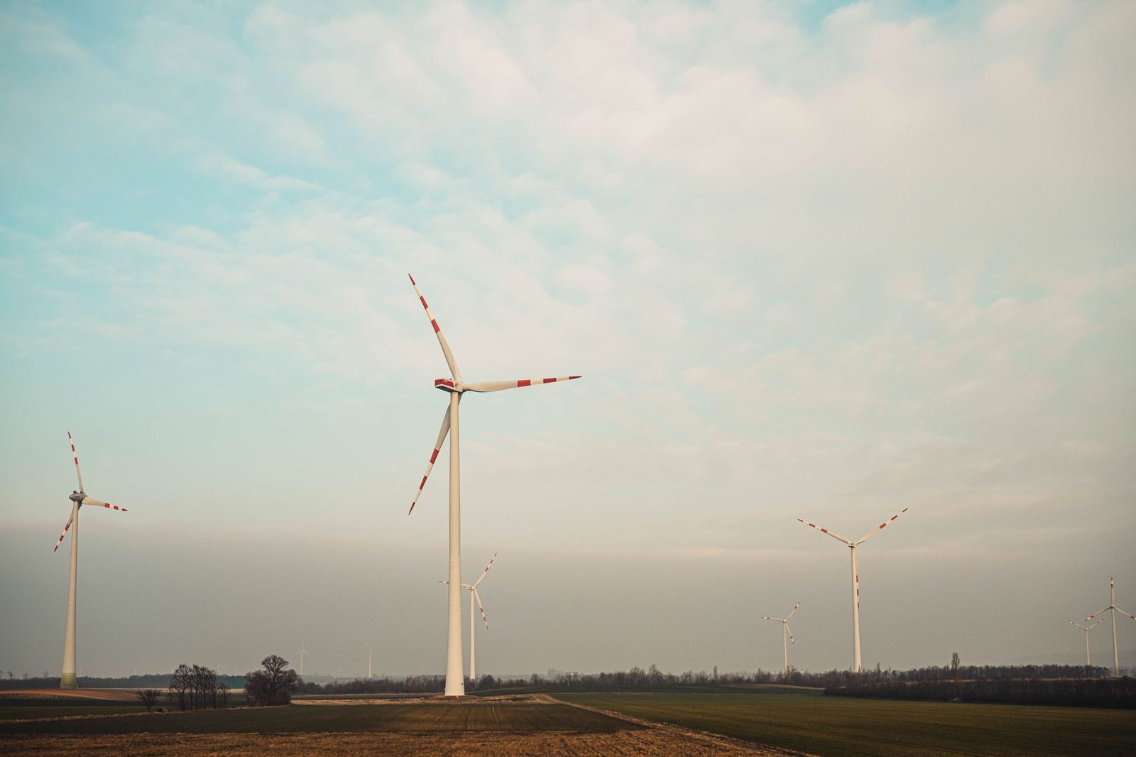 Wind turbines on a field under a cloudy sky, capturing clean renewable energy.