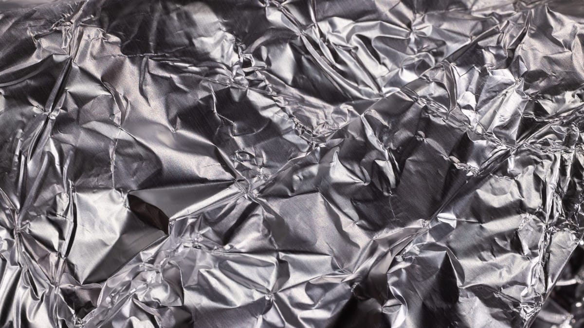 Close-up of shiny crumpled aluminum foil showcasing metallic wrinkled texture.