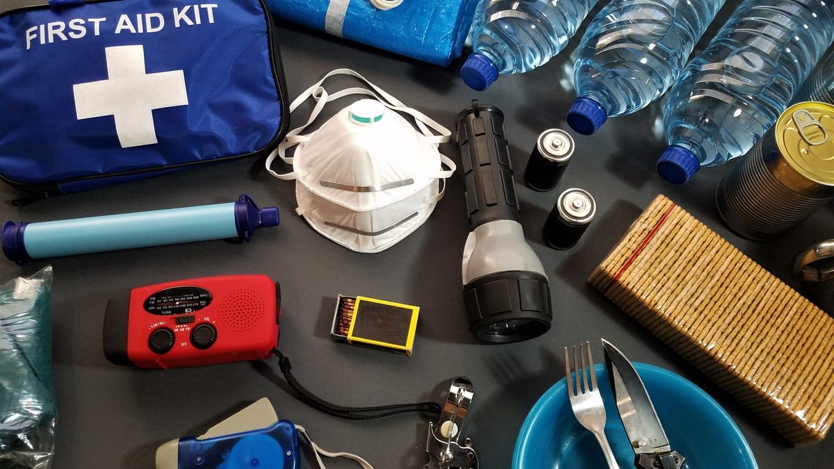 Flat lay of essential emergency survival kit items including first aid and water bottles.