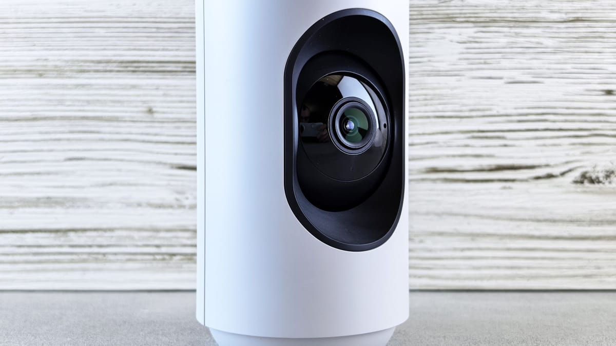 Close-up of a white indoor security camera against a wooden backdrop, showcasing modern design.