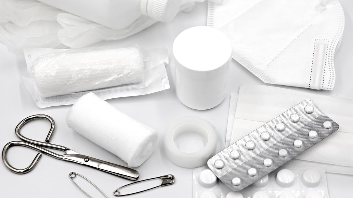 A flat lay of essential first aid supplies and medical equipment on a white background.