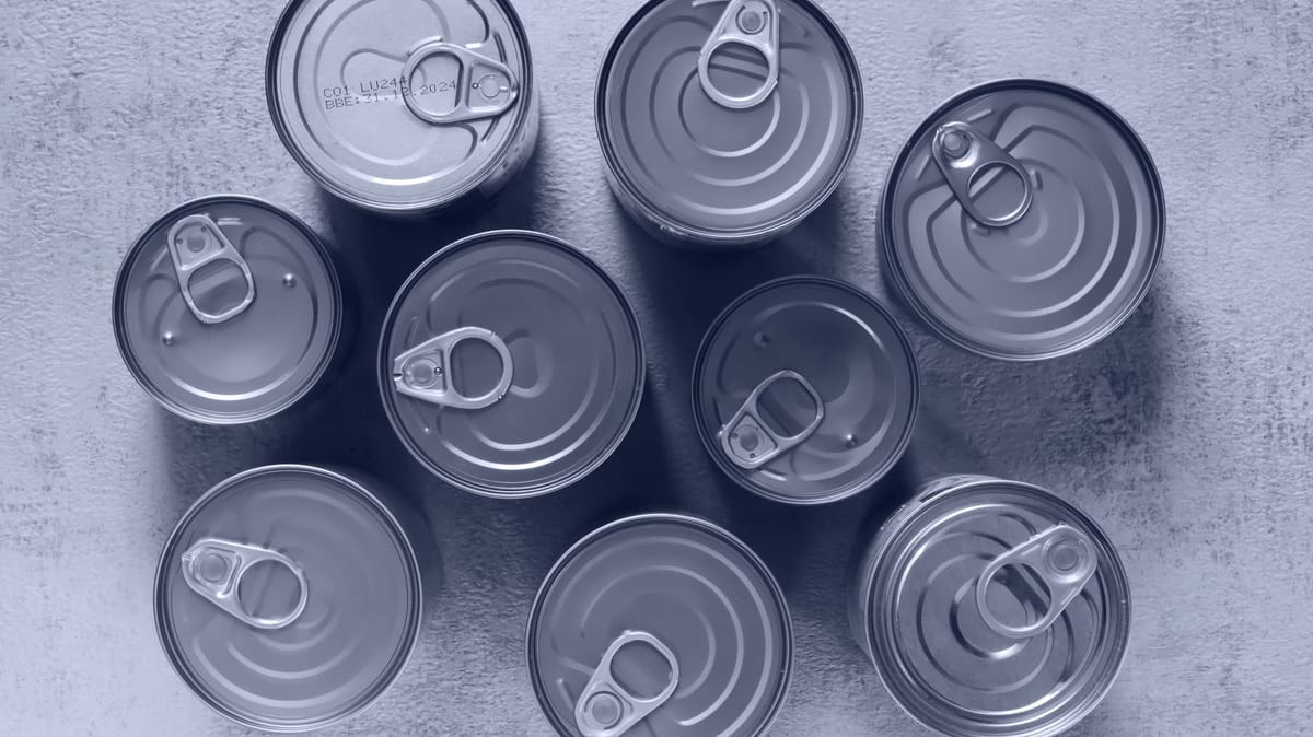 High-angle shot of canned food tins arranged on a rough surface, emphasizing texture and symmetry.