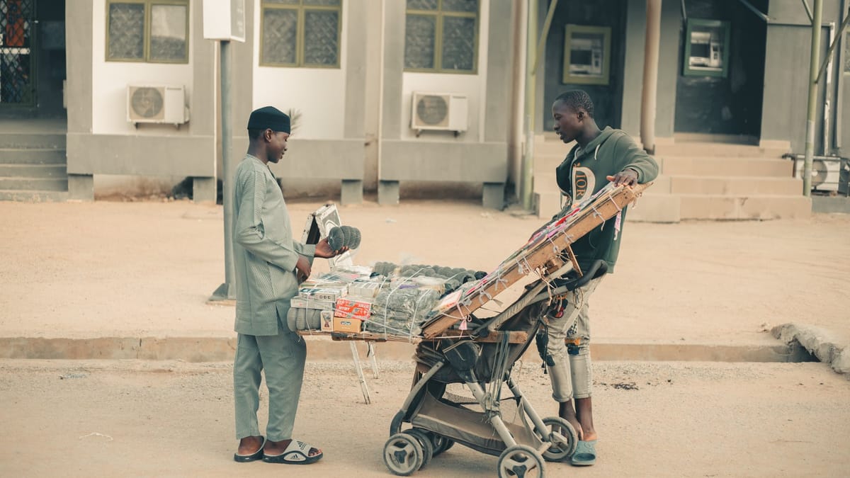 Urban street scene showing a vendor selling traditional goods to a customer.