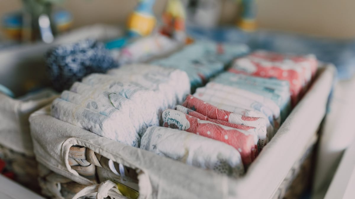 Close-up of neatly arranged colorful baby diapers in a woven basket, ideal for nursery organization.