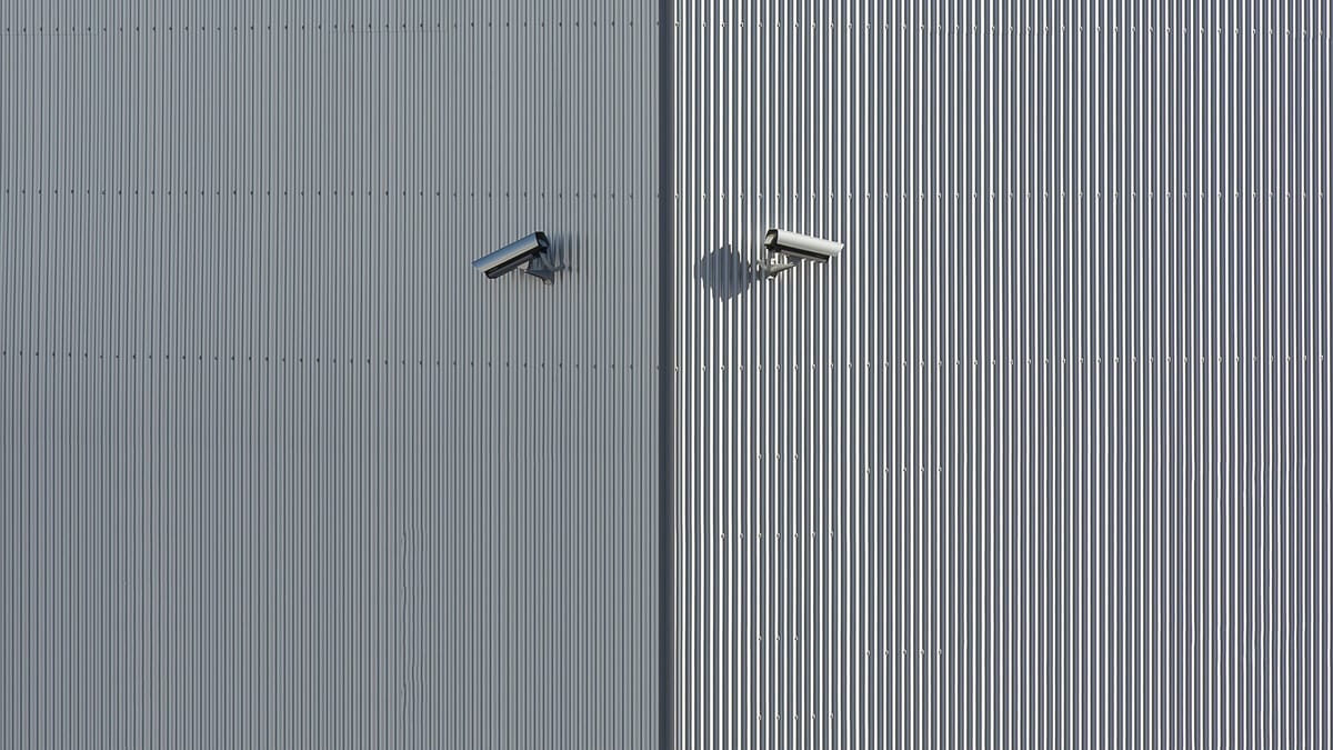 Corrugated metal wall with two mounted security cameras in a minimalist style.