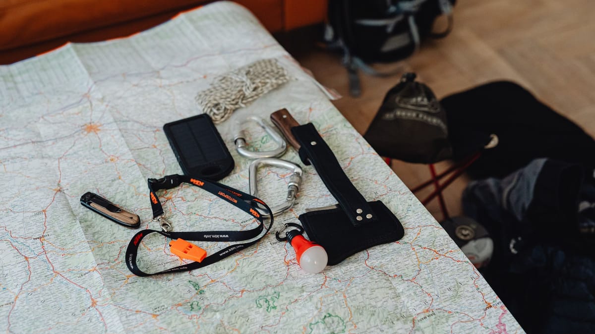 A collection of travel tools and gear laid out on a map, ready for an outdoor adventure.
