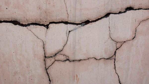 Close-up of a cracked concrete wall, showcasing its unique texture and patterns.