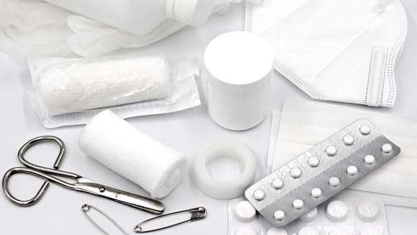 A flat lay of essential first aid supplies and medical equipment on a white background.