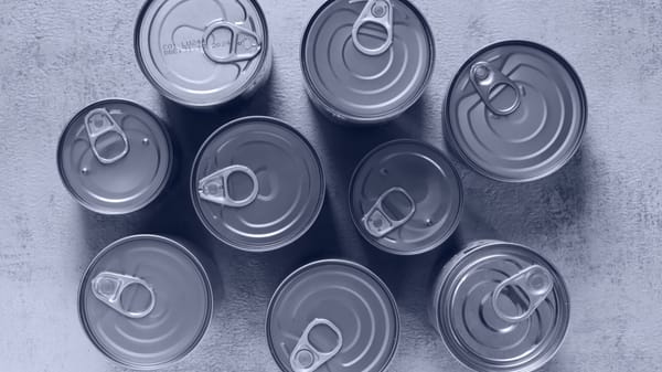 High-angle shot of canned food tins arranged on a rough surface, emphasizing texture and symmetry.