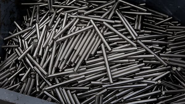 Close-up of numerous stainless steel rods in a container, showcasing industrial metal texture.