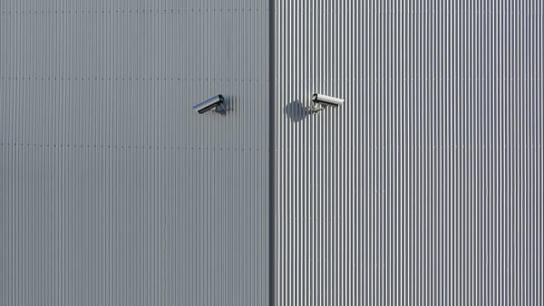 Corrugated metal wall with two mounted security cameras in a minimalist style.