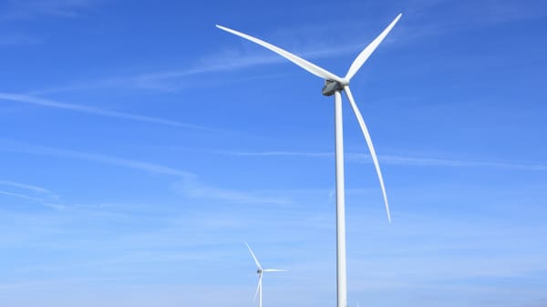 Wind turbines under a clear blue sky symbolize clean energy and sustainability.