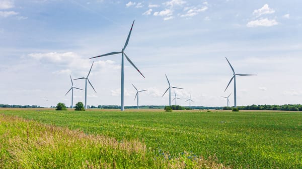 Wind turbines generating clean energy in a lush green landscape under a clear blue sky.