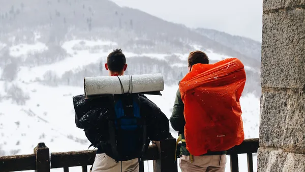 Two male hikers with backpacks enjoying a snowy mountain view in winter.