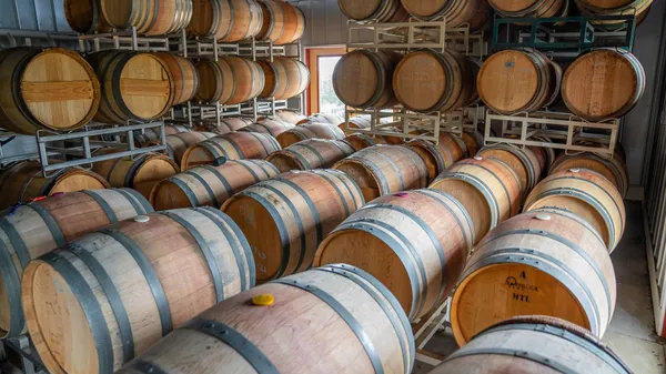 A room filled with neatly arranged wooden wine barrels in a North Carolina storage cellar.