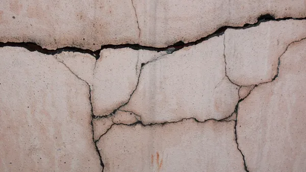 Close-up of a cracked concrete wall, showcasing its unique texture and patterns.
