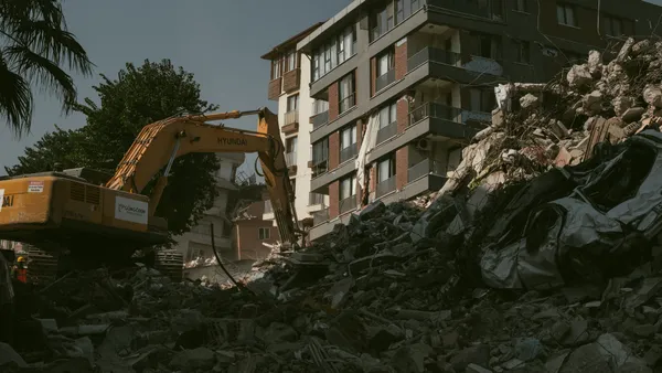 Excavator removing rubble from a collapsed building area in Antakya, Türkiye.