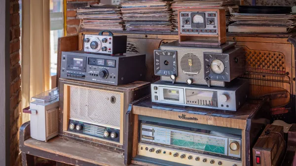 A charming interior featuring a collection of vintage radios and a stack of vinyl records on an antique wooden cabinet.