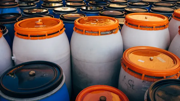Close-up of blue and white plastic barrels with orange lids in storage area.