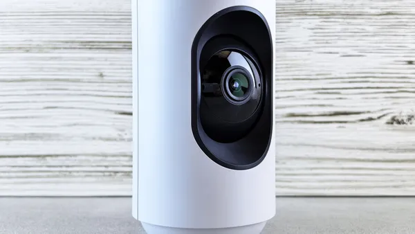 Close-up of a white indoor security camera against a wooden backdrop, showcasing modern design.