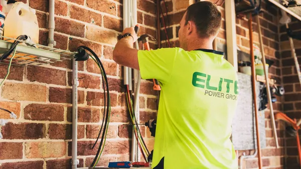 Electrician performing solar battery installation for sustainable energy storage in a home setting.