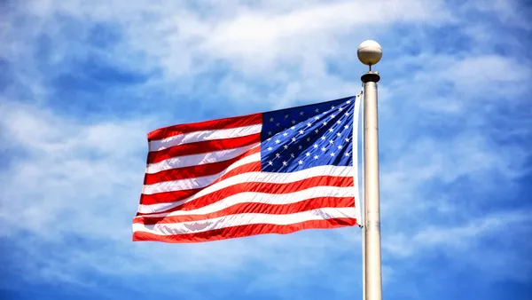 Vibrant American flag flying against a clear blue sky, symbolizing freedom and patriotism.