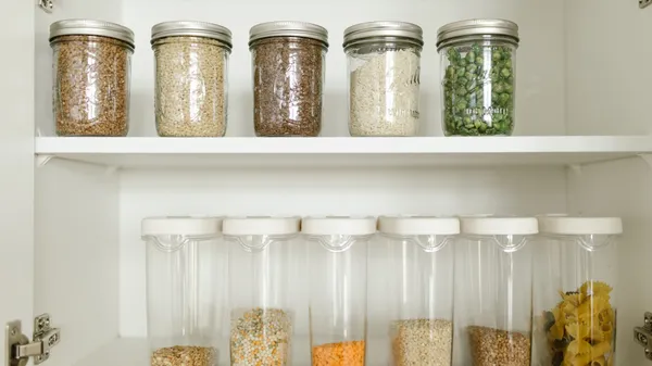 Neatly arranged pantry showcasing grains in glass jars and dry goods in plastic containers.