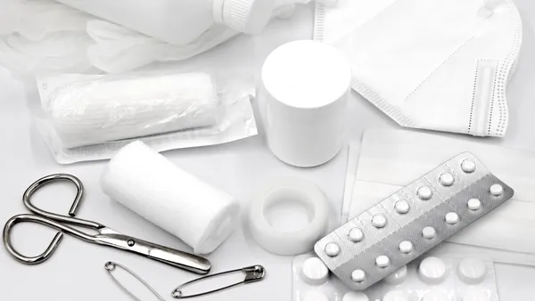 A flat lay of essential first aid supplies and medical equipment on a white background.