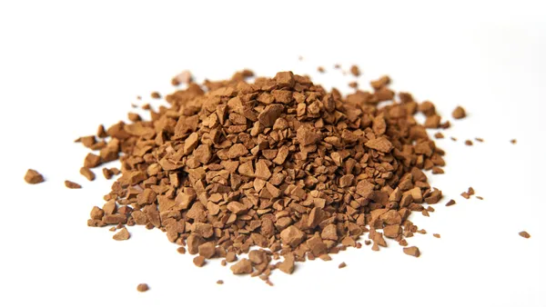 Macro shot of coarse brown coffee granules piled on a clean white background, perfect for caffeine lovers.