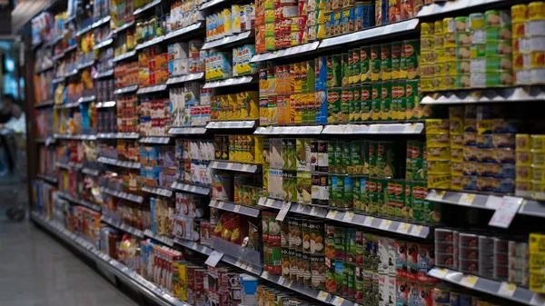 A supermarket aisle filled with various canned goods on shelves, showcasing retail diversity.